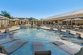 A large outdoor pool surrounded by lounge chairs at Crossgates Apartment Homes, Starkville, Mississippi